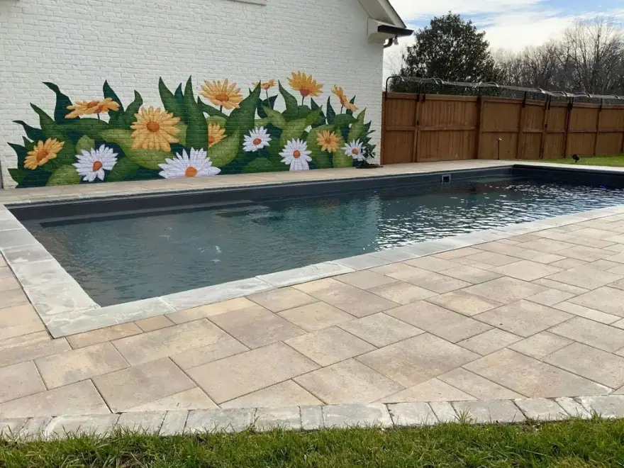 A paver pool deck beside a dark finish rectangular swimming pool built by Allin Landscaping
